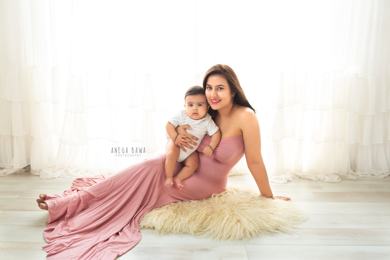 Indulge in a serene family moment with Mom and Son sitting on a beige rug against a pure white backdrop. Experience the magic of Anega Bawa Photography in Delhi and Gurgaon, immortalizing your cherished bond in timeless photographs.