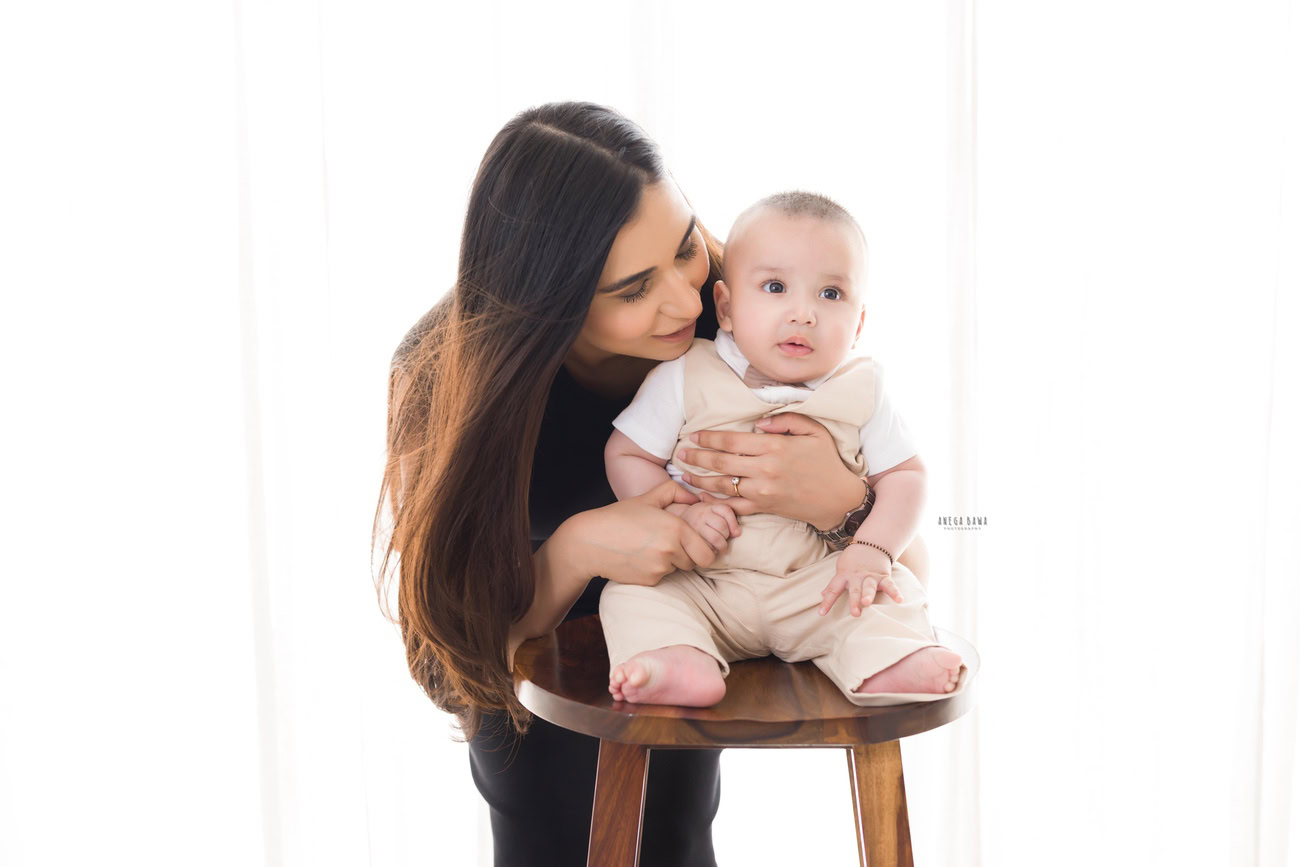 Capture the essence of family love with a delightful photoshoot featuring Mom and Son sitting on a wooden stool against a clean white backdrop. Let Anega Bawa Photography in Delhi and Gurgaon preserve these precious moments for you to cherish forever.