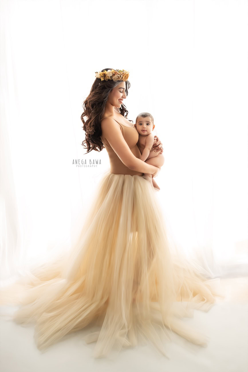 Create beautiful memories with Anega Bawa Photography in Delhi and Gurgaon. Capture endearing moments of Mumma and her son, where Mumma dons a beige net dress, against a serene white backdrop, encapsulating the love and warmth of family bonds.