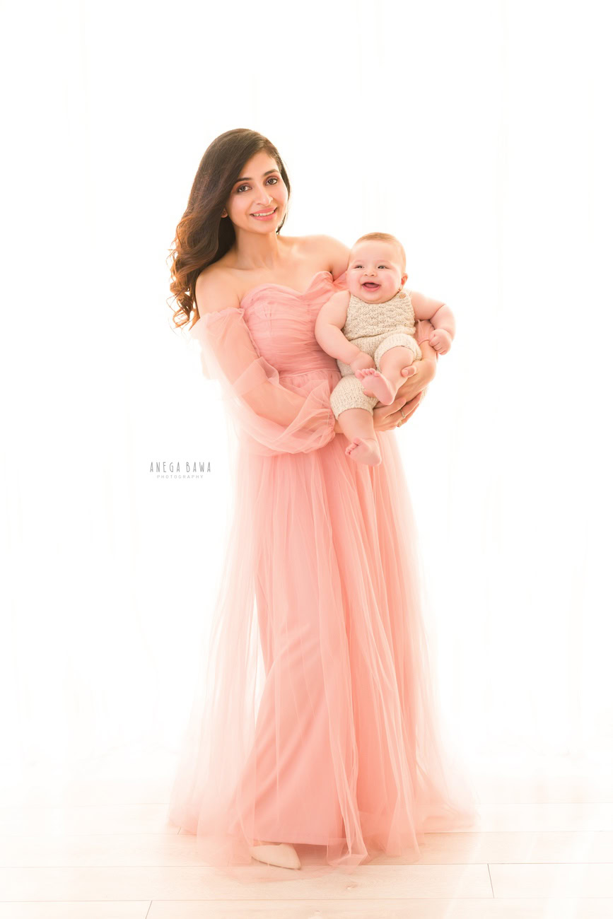 Capture the essence of love and tenderness with Anega Bawa Photography in Delhi and Gurgaon. Mumma shines in a graceful peach gown as she holds her son close against a pristine white backdrop, creating timeless memories filled with warmth and affection.