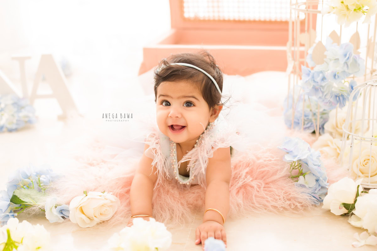 In this enchanting sitter photoshoot by Anega Bawa in Delhi, Gurgaon, a 12-month-old girl is captured in a moment of exploration. Crawling on a soft pink rug adorned with tiny white castles, she exudes innocence and curiosity.