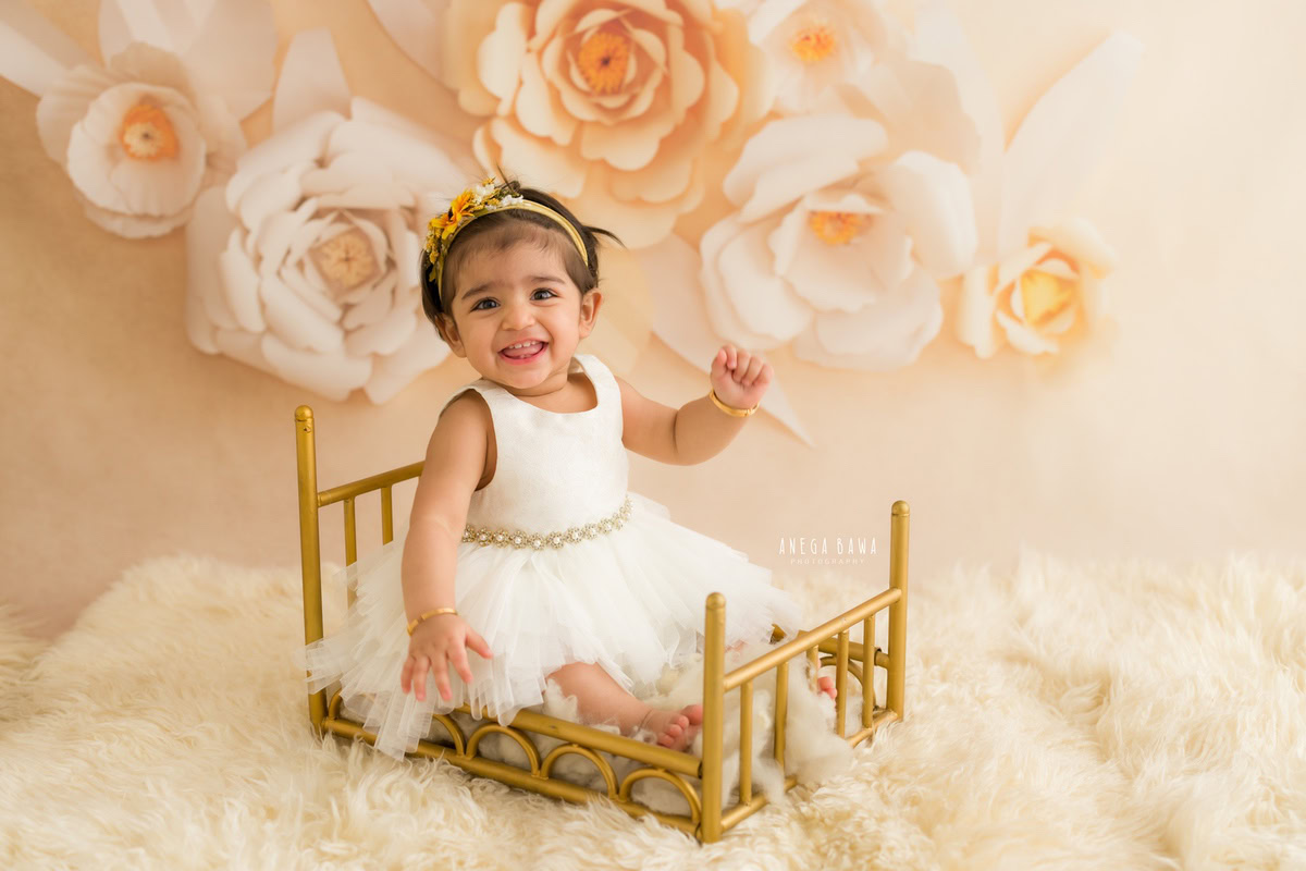 In Anega Bawa's lens, your 8-month-old princess shines like a golden star, seated gracefully in a lavish cot. Against a backdrop of peachy florals and adorned with a white rug, her innocence and beauty are immortalized in every click. Experience the magic of sitter photography in Delhi and Gurgaon as your little one becomes the star of the frame.