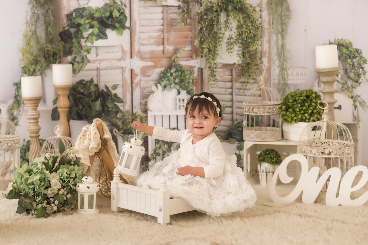 Experience the ethereal charm as your little princess sits gracefully in a pristine white cot, clutching a delicate white castle. Bathed in the soft glow of candlelight against a backdrop of pure white, each moment is a precious treasure to behold. With Anega Bawa Photography in Delhi and Gurgaon, capture the innocence and beauty of your 8-month to 1-year-old in timeless portraits.