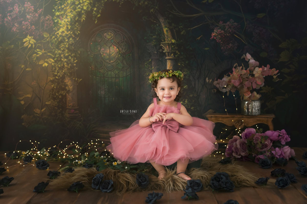 Delight in the enchanting innocence of your 15-month to 1-year-old girl as she sits gracefully amidst the warm glow of fairy lights on a soft brown rug. Against a backdrop of lush leafy greens and earthy brown hues, let Anega Bawa Photography in Delhi and Gurgaon capture these magical moments forever. Book your sitter photography session today!