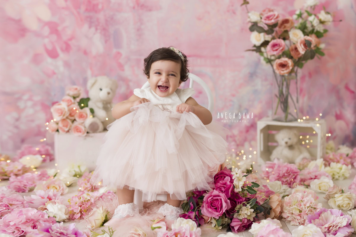 In Gurgaon and Delhi, Anega Bawa captures the sweetness of a 16-month-old girl seated on a white chair against a pink backdrop. Accompanied by a cuddly teddy bear, the scene is further enchanted by twinkling fairy lights and scattered flowers on the floor. It's a delightful moment expertly immortalized by Anega Bawa, offering a glimpse into the innocence and joy of childhood.