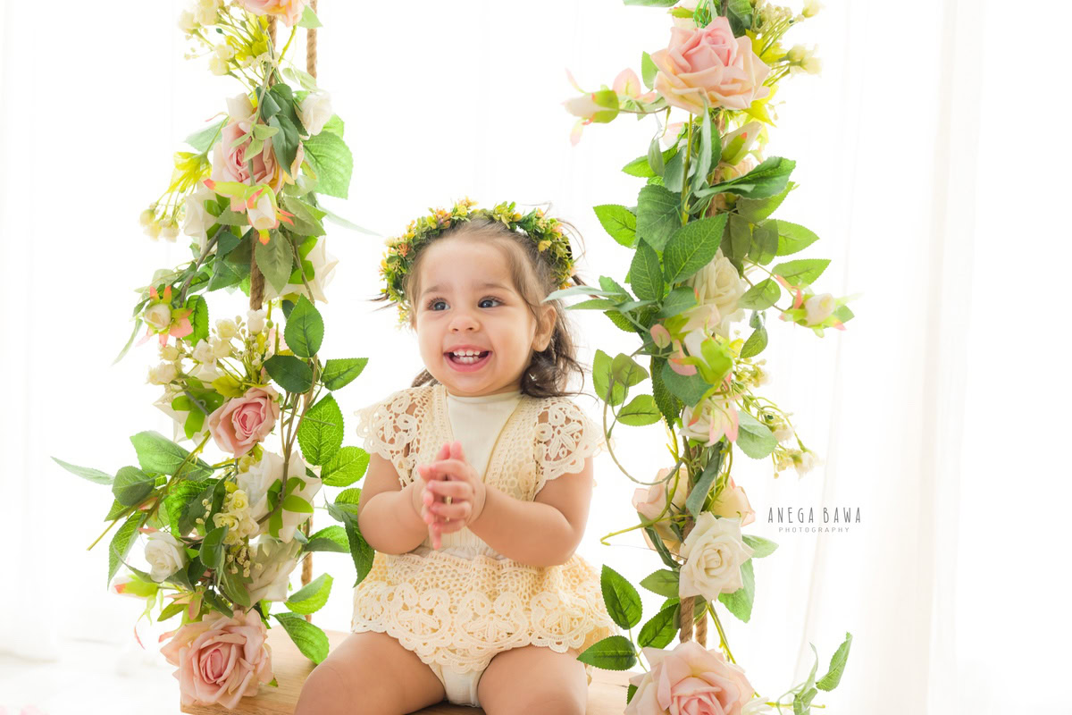 In this sweet capture by Anega Bawa, a 16-month-old girl beams with joy as she poses on a swing against a serene white backdrop. Her radiant smile lights up the frame, capturing the innocence and happiness of toddlerhood in Delhi, Gurgaon, or Noida.