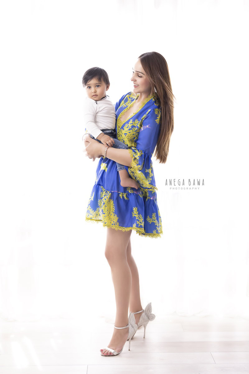 1-year-old boy in mom's arms against a pure white backdrop, capturing a tender moment. This family photo shoot is done by Anega Bawa Photography in Gurgaon (Delhi NCR), your go-to expert for creating precious family memories.