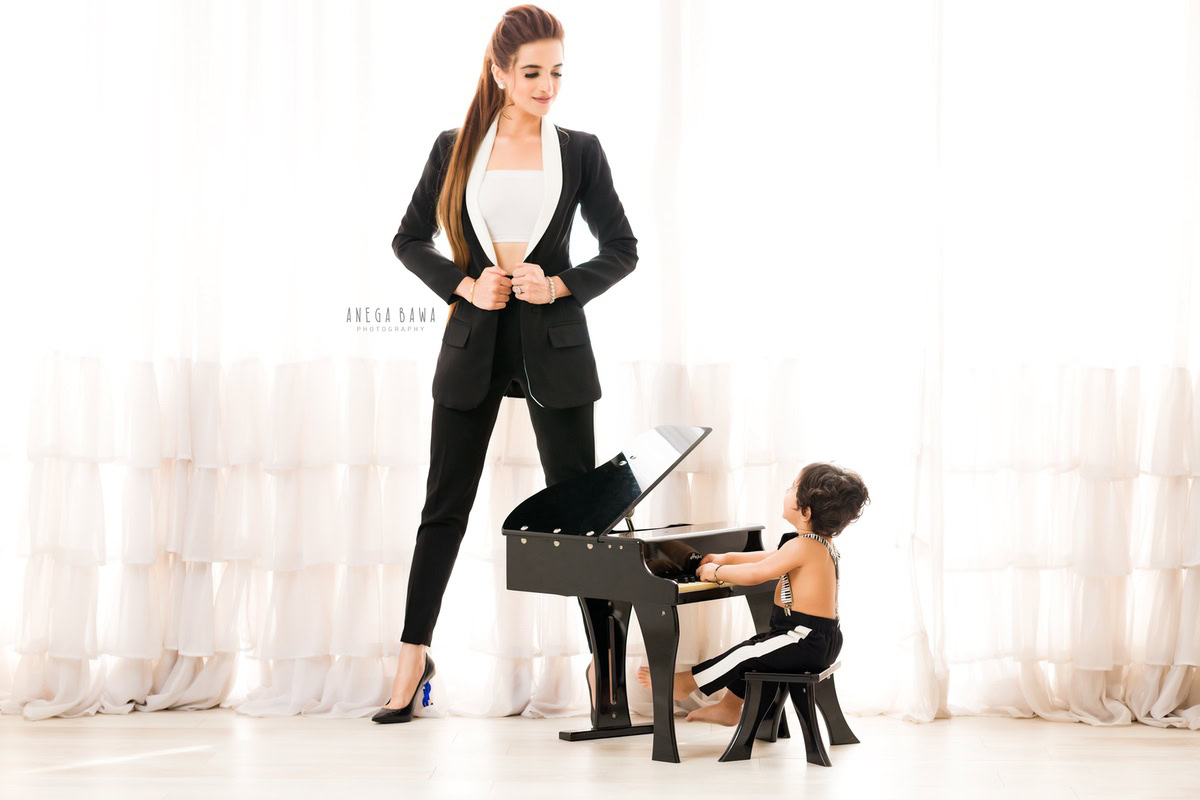 1-year-old boy playing the piano with mom posing beautifully against a serene white backdrop. Capture this precious moment with Anega Bawa Photography, your expert for family photo shoots in Gurgaon (Delhi NCR).