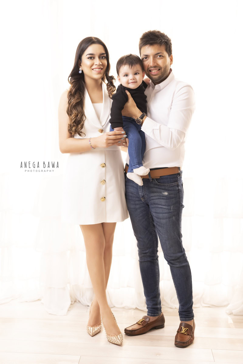 1-year-old boy posing with mom and dad against a white backdrop. Family photo shoot is done by Anega Bawa Photography in Gurgaon (Delhi NCR) to capture these timeless memories.