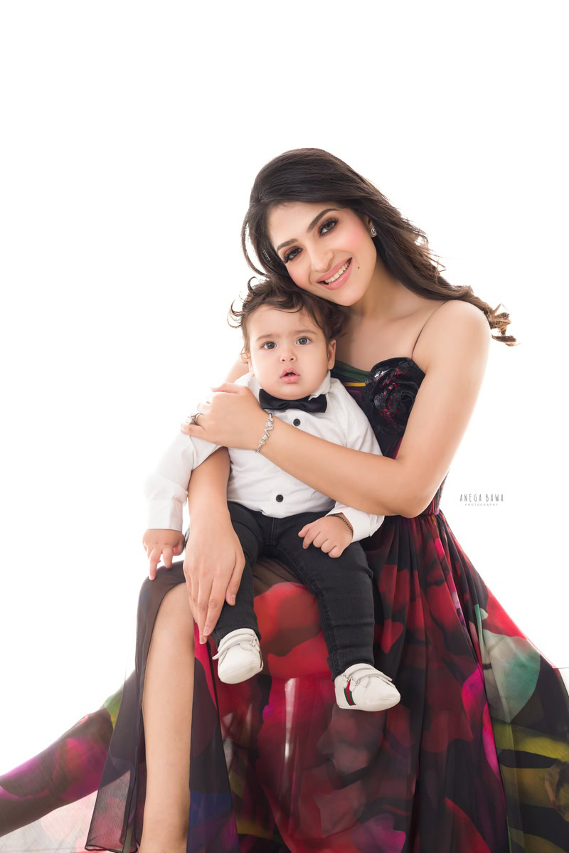 1-year-old boy posing cutely with mom in a hugging pose against a white backdrop, family photoshoot in Gurgaon (Delhi NCR)