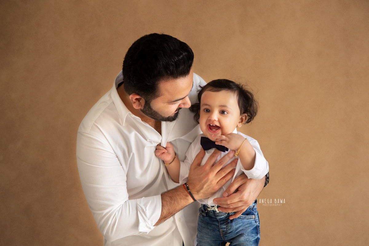 1-year-old boy posing with dad against a brown backdrop, family photoshoot in Gurgaon (Delhi NCR)
