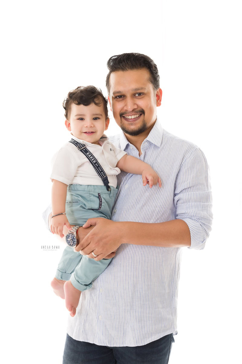 1-year-old boy posing with dad against a clean white backdrop. Captured by Anega Bawa Photography, Gurgaon (Delhi NCR).