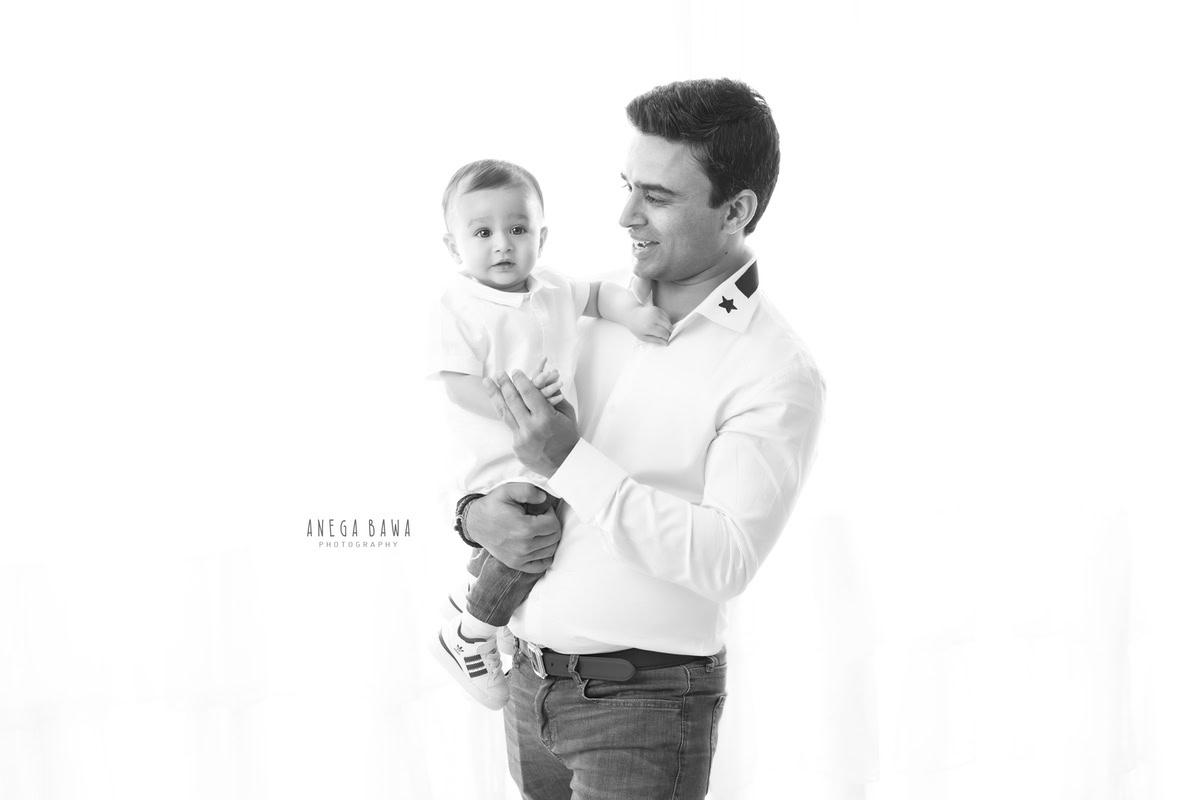 1-year-old boy posing with dad against a white backdrop, captured by Anega Bawa Photography for a family photoshoot in Gurgaon (Delhi NCR).