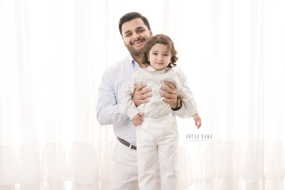 1-year-old boy posing with dad against a white backdrop, captured by Anega Bawa Photography for a family photoshoot in Gurgaon (Delhi NCR).