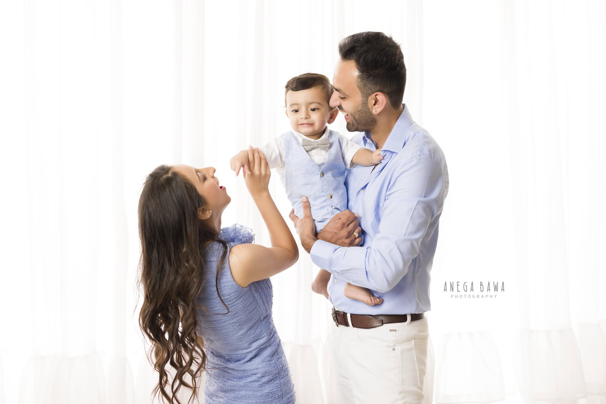 1-year-old boy posing with mom and dad in a playful pose against a white backdrop, family photoshoot in Gurgaon (Delhi NCR)