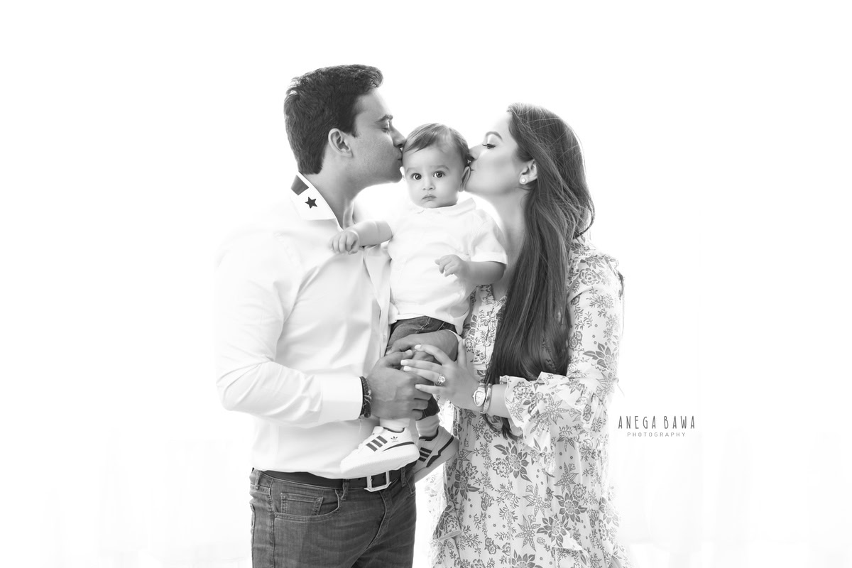 1-year-old boy posing with mom and dad against a white backdrop, family photoshoot in Gurgaon (Delhi NCR)
