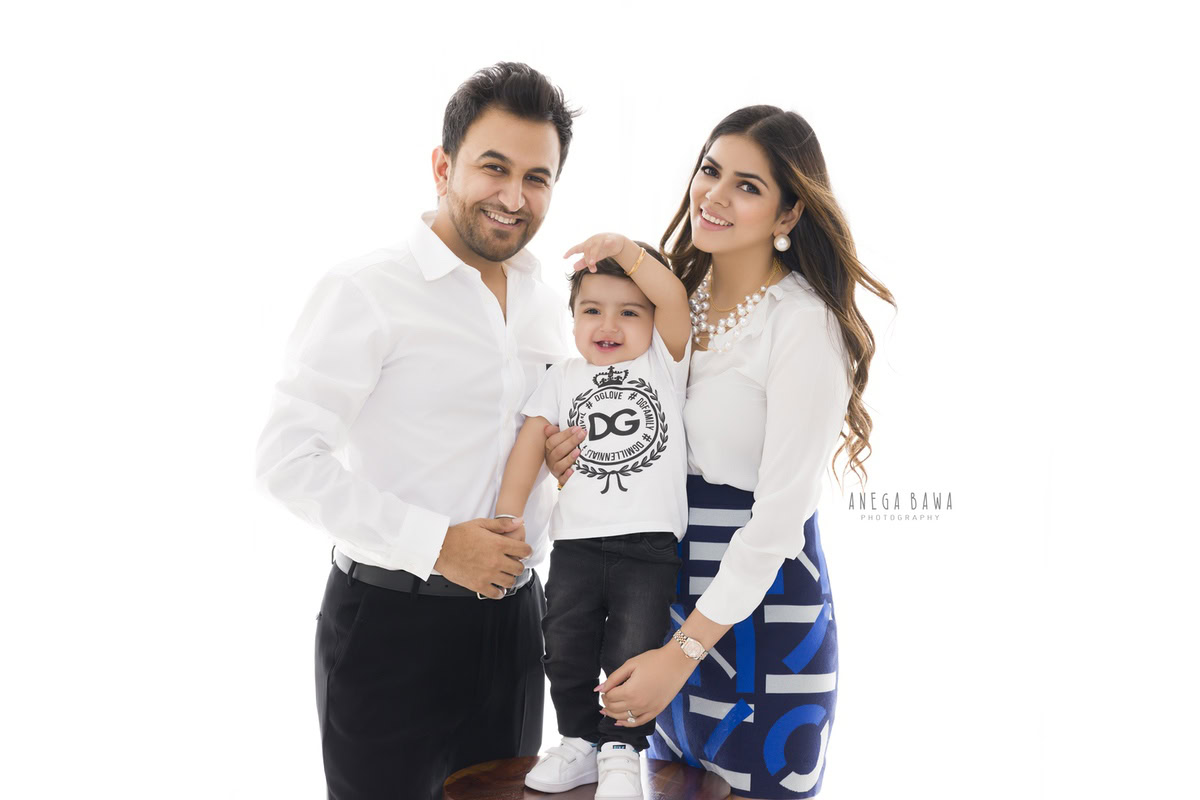 1-year-old boy posing with mom and dad against a white backdrop, family photoshoot in Gurgaon (Delhi NCR)