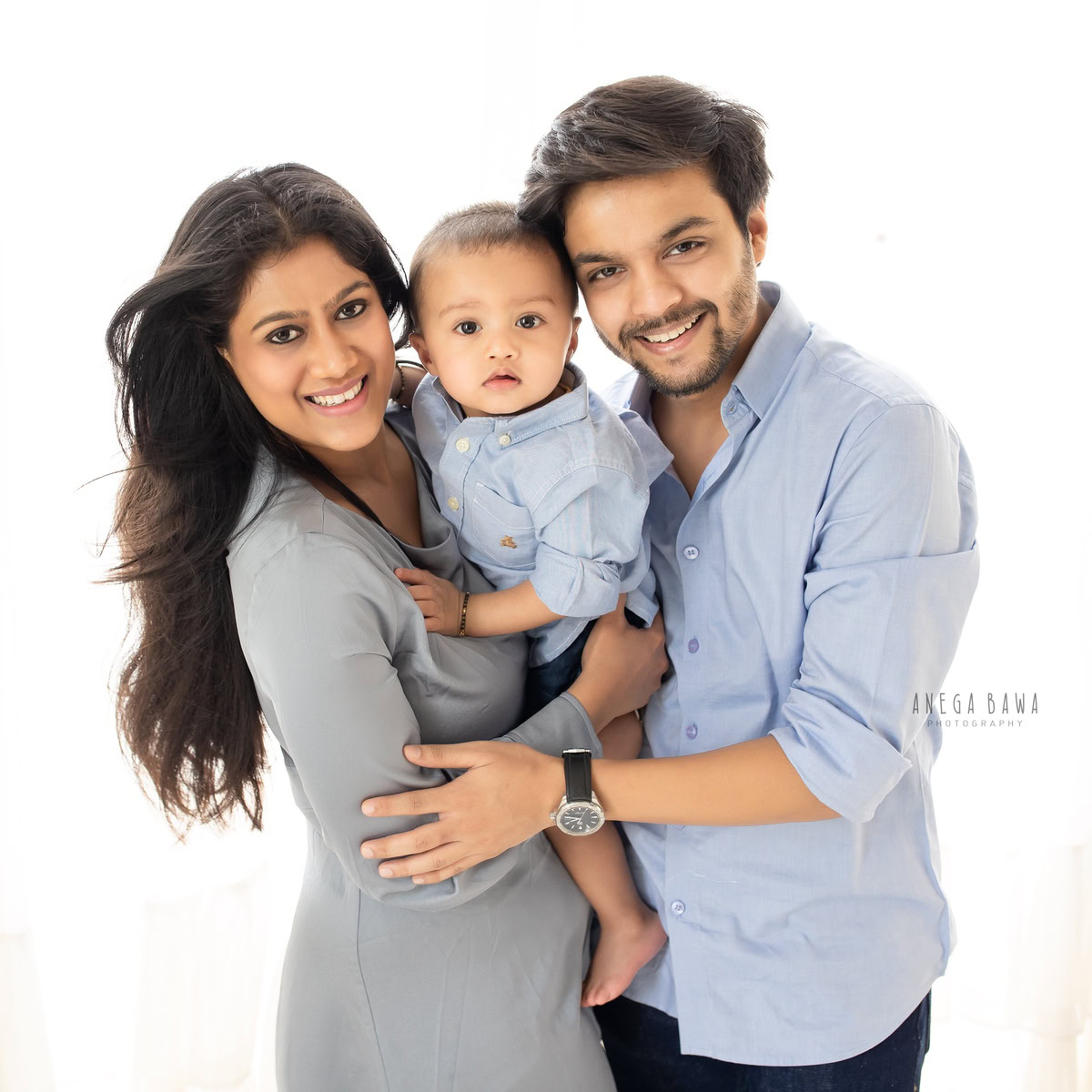 1-year-old boy posing with mom and dad against a white backdrop, family photoshoot in Gurgaon (Delhi NCR)