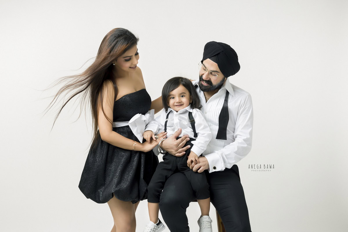 1-year-boy posing with mom and dad against a pristine white backdrop, beautifully photographed by Anega Bawa Photography for a family photoshoot in Gurgaon (Delhi NCR).