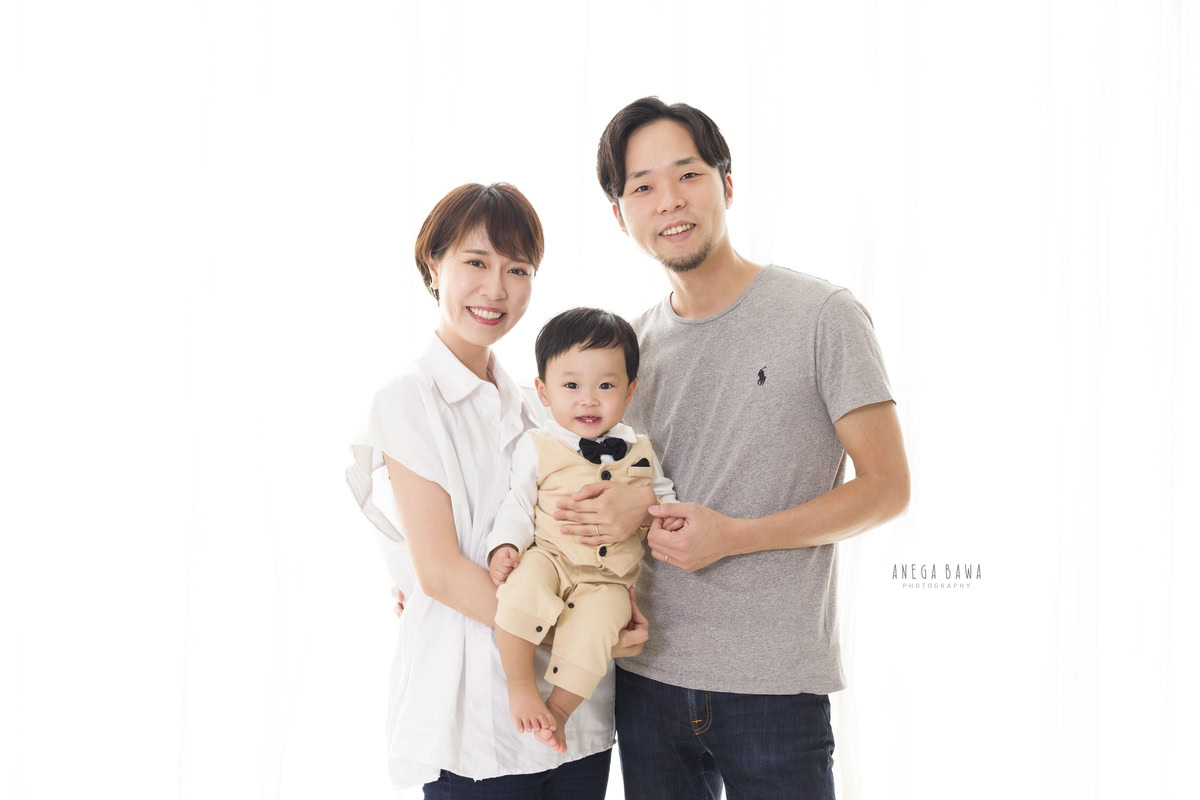 1-year-old boy posing with mom and dad against a white backdrop, captured by Anega Bawa Family Photographer Gurgaon (Delhi NCR).