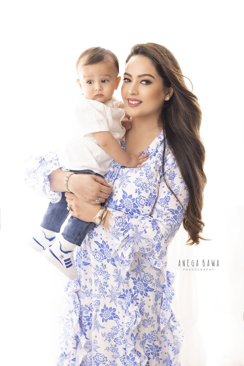 1-year-old boy posing with mom against a serene white backdrop, beautifully captured by Anega Bawa Photography for a family photoshoot in Gurgaon (Delhi NCR).