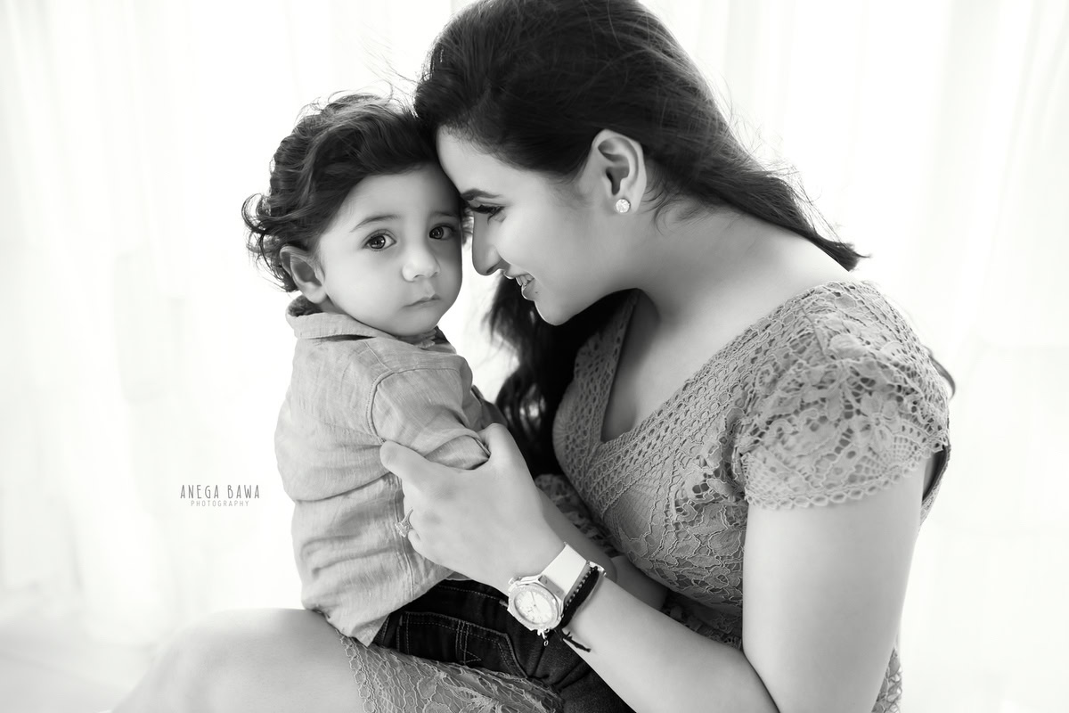 1-year-old boy posing with mom against a white backdrop, captured by Anega Bawa Family Photographer Gurgaon (Delhi NCR).