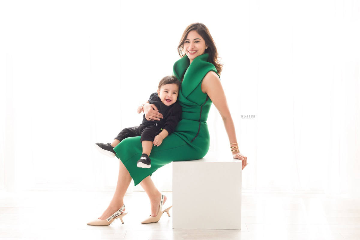 1-year-old boy seated on mom's lap against a white backdrop, family photoshoot in Gurgaon (Delhi NCR)