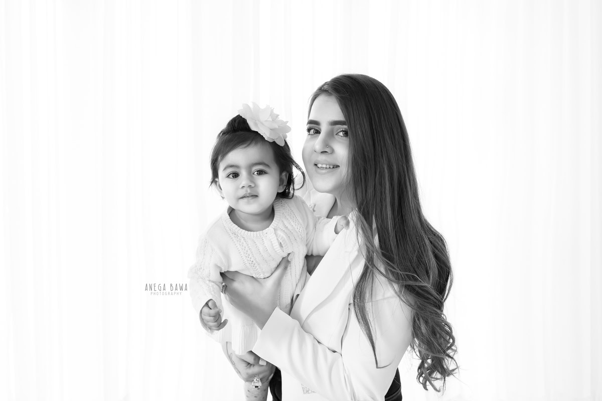 1-year-old daughter posing with mom in a black and white pose against a white backdrop, captured by Anega Bawa Family Photographer Gurgaon (Delhi NCR).