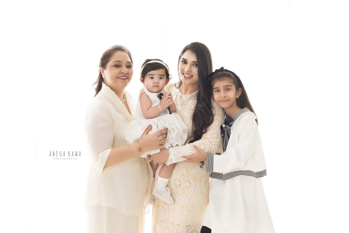 1-year-old girl in a fairy dress joyfully posing with her elder brother, mom, and dad in a heartwarming family portrait against a serene white backdrop. Captured by Anega Bawa Photography, ensuring memorable family moments in Gurgaon (Delhi NCR).