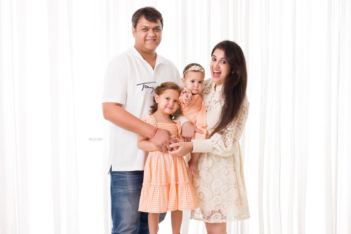 "1-year girl posing with dad, mom, and elder sister against a clean white backdrop, captured by Anega 1-year girl posing with dad, mom, and elder sister against a clean white backdrop, captured by Anega Bawa Photography in Gurgaon (Delhi NCR).