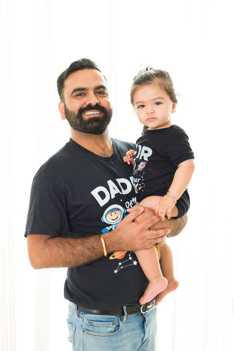 1-year girl posing with dad against a serene white backdrop, photographed by Anega Bawa Photography in Gurgaon (Delhi NCR)