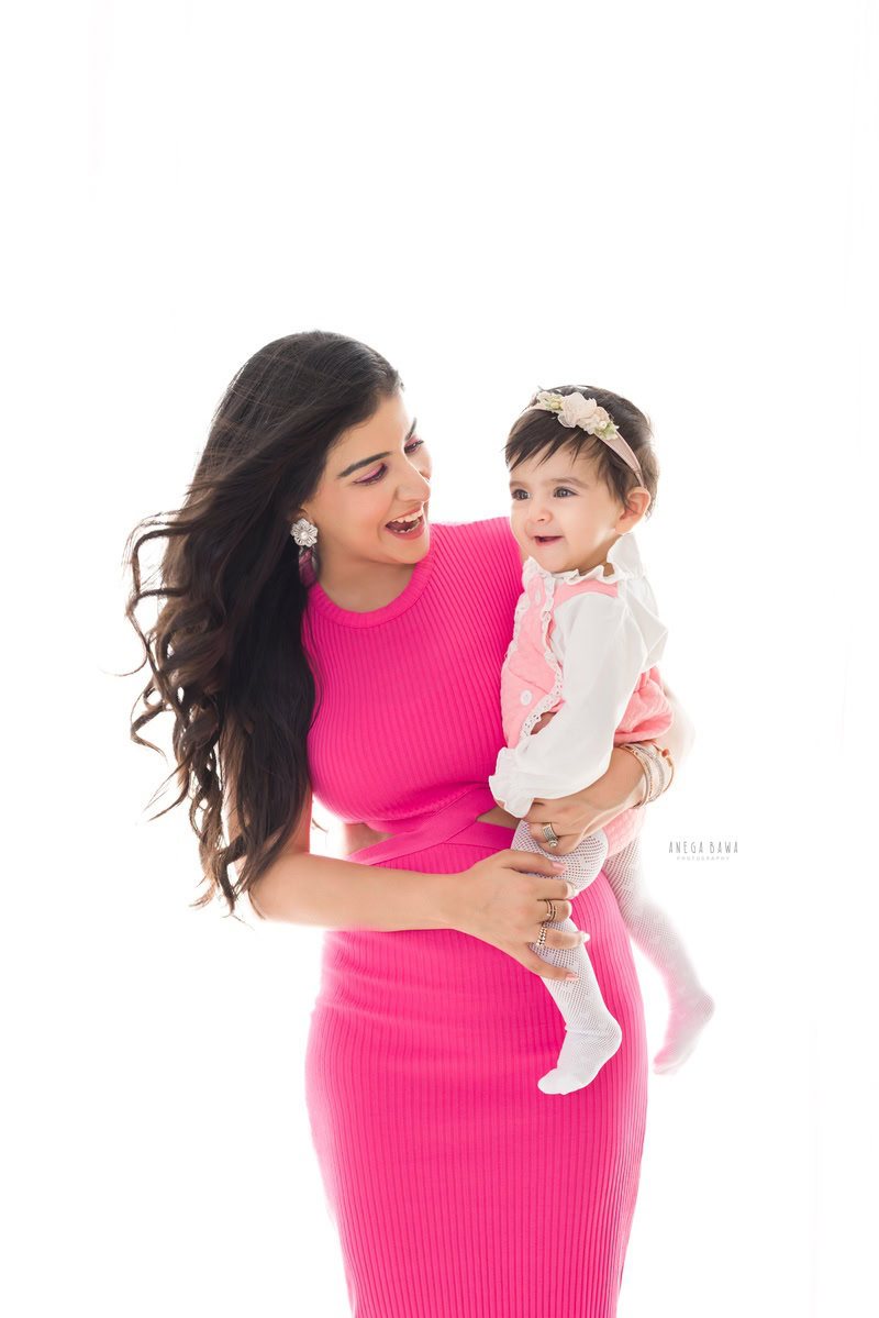 1-year-old girl posing with mom wearing a cute headband against a white backdrop, captured by Anega Bawa Family Photographer Gurgaon (Delhi NCR).