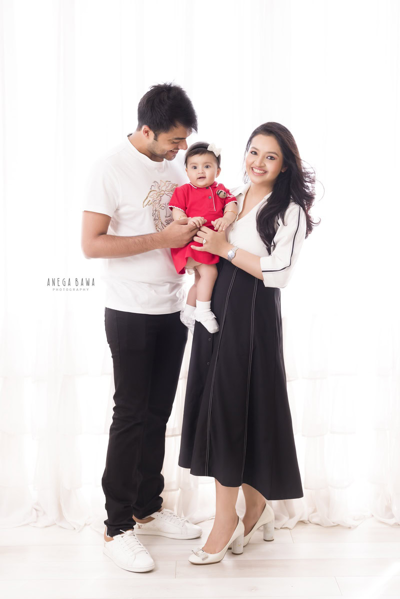 1-year-old girl posing with mom and dad against a white backdrop, family photoshoot by Anega Bawa, Gurgaon (Delhi, NCR)