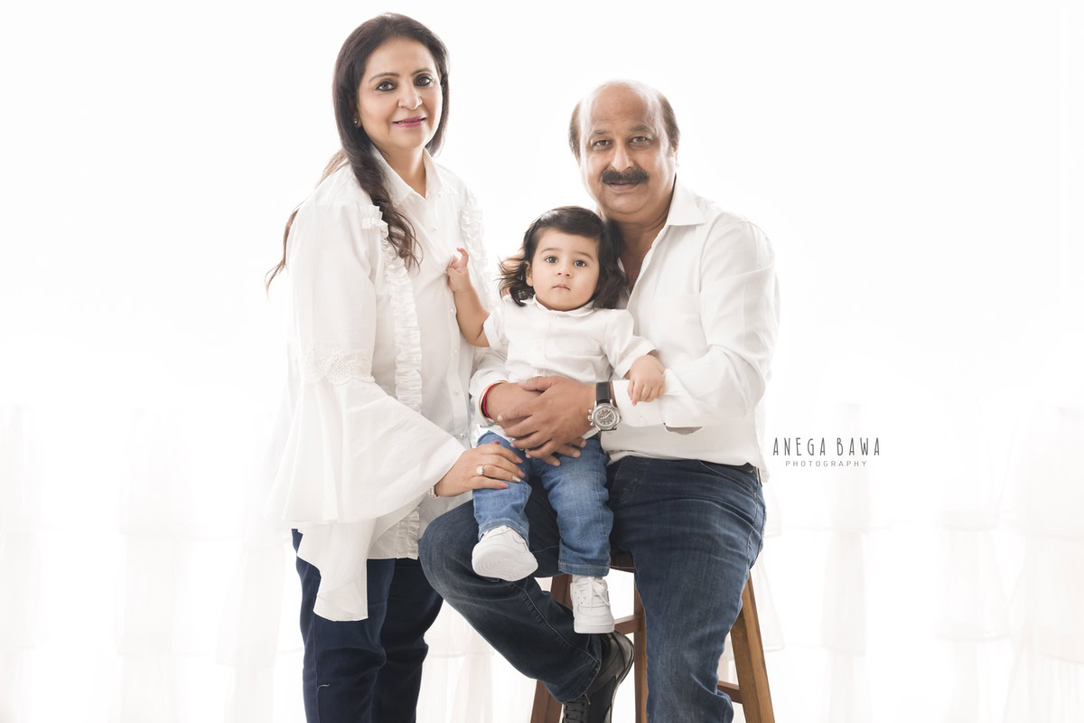 1-year-old girl posing with mom and dad against a white backdrop, captured by Anega Bawa Family Photographer Gurgaon (Delhi NCR).