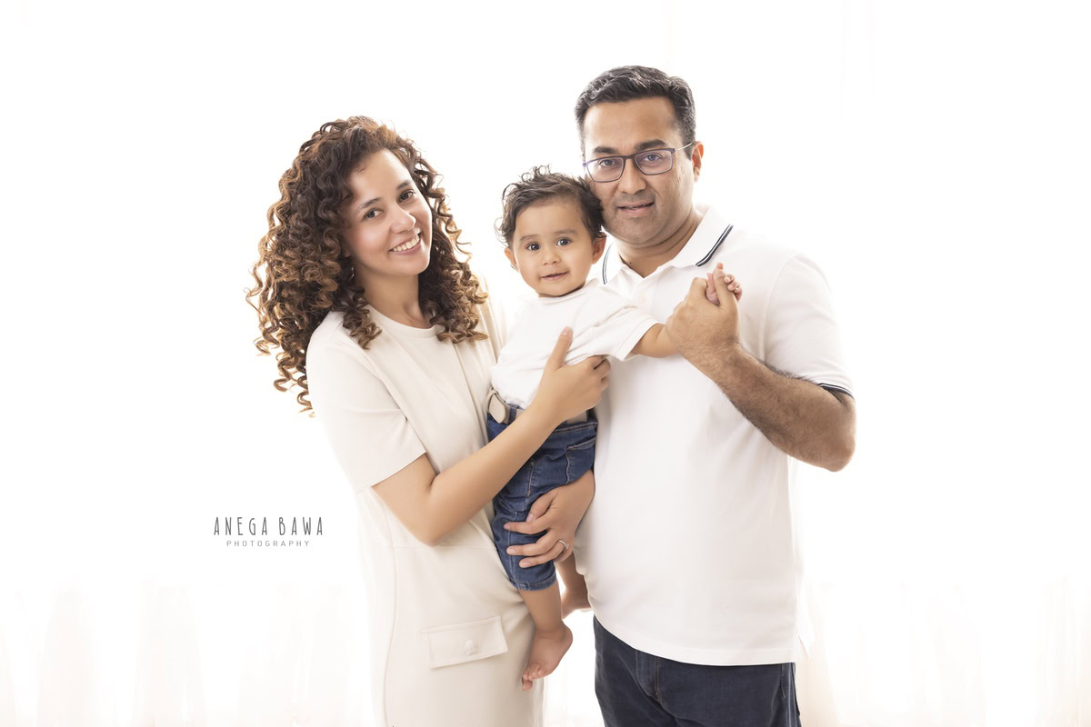 1-year-old girl posing with mom and dad against a white backdrop, family photoshoot by Anega Bawa, Gurgaon (Delhi, NCR)