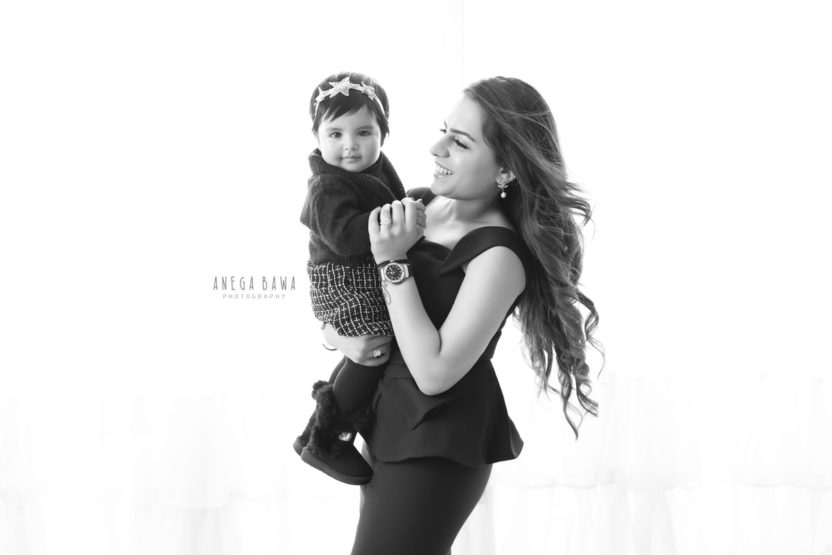 1-year-old girl posing with mom, wearing a cute headband, against a white backdrop, family photoshoot by Anega Bawa, Gurgaon (Delhi, NCR)