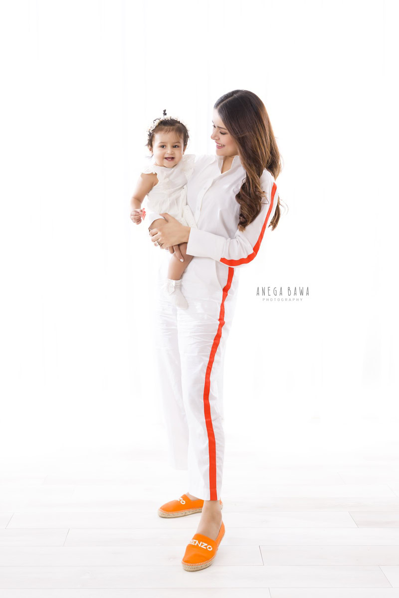 Charming 1-year-old girl posing with her mom against a clean white backdrop. Captured by Anega Bawa Photography, this precious moment is part of a family photo shoot in Gurgaon (Delhi NCR), highlighting the bond between mother and daughter.