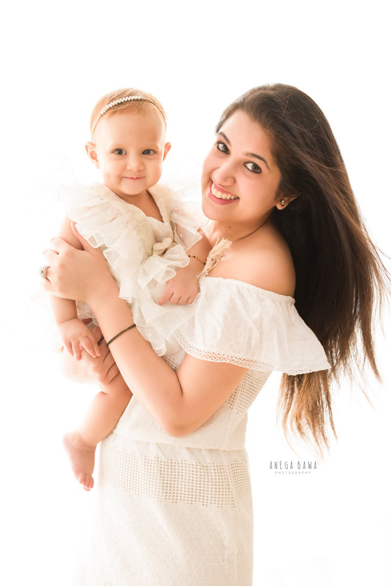 1-year-old girl posing with mom against a white backdrop, captured by Anega Bawa, family photographer in Gurgaon (Delhi NCR).