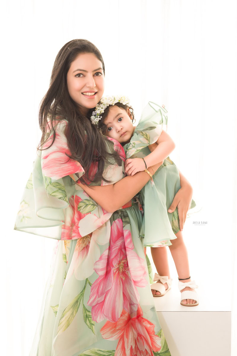 1-year-old girl wearing a tiara band, hugging mom against a white backdrop. Captured by Anega Bawa Photography, Gurgaon (Delhi, NCR).