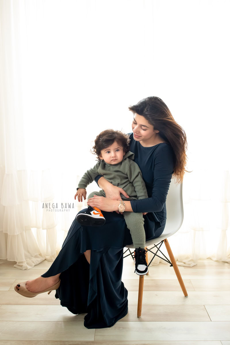 1-year-old son seated on mom's lap against a white backdrop, captured by Anega Bawa, family photographer in Gurgaon (Delhi NCR).