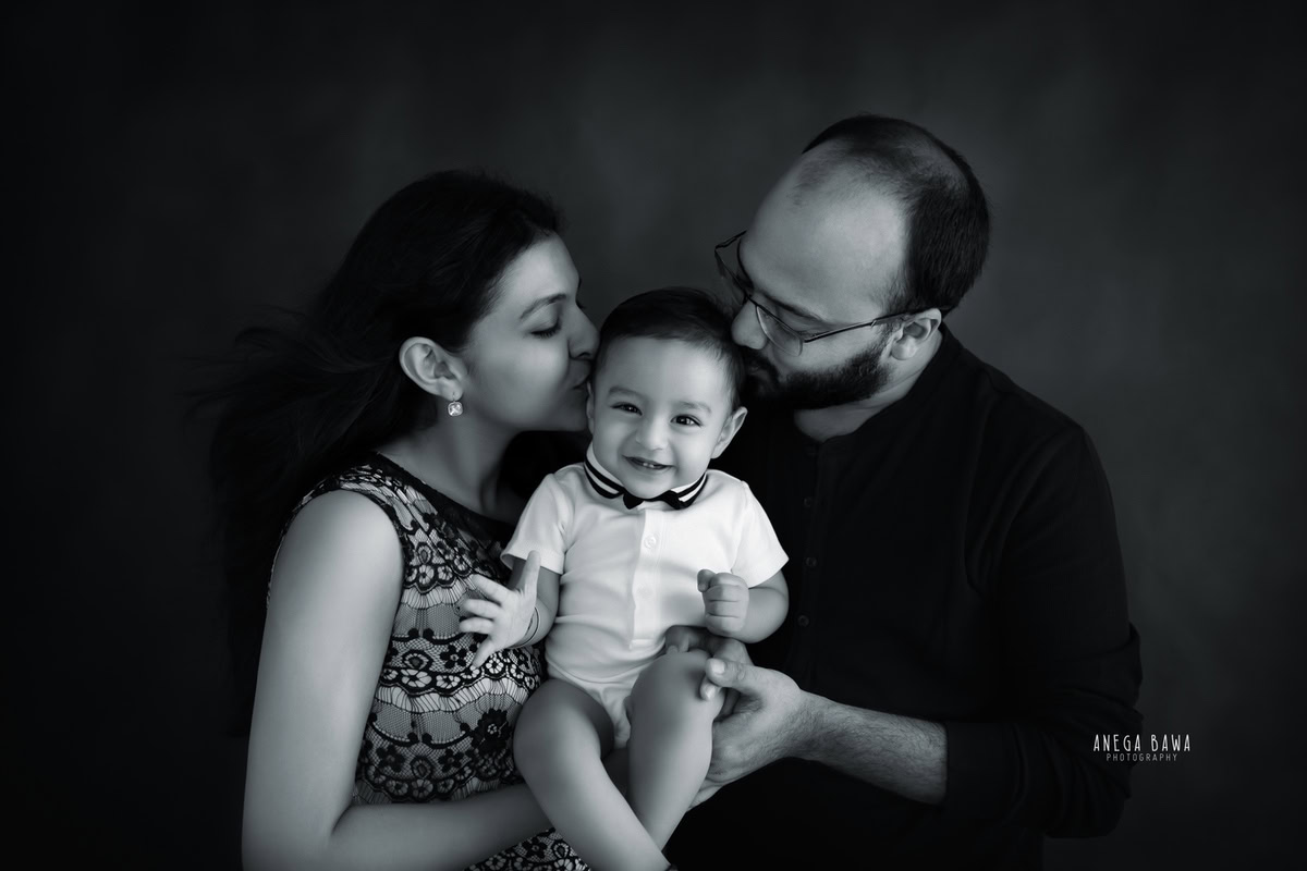 10-months-boy in a cute pose with mom and dad against a black and white backdrop