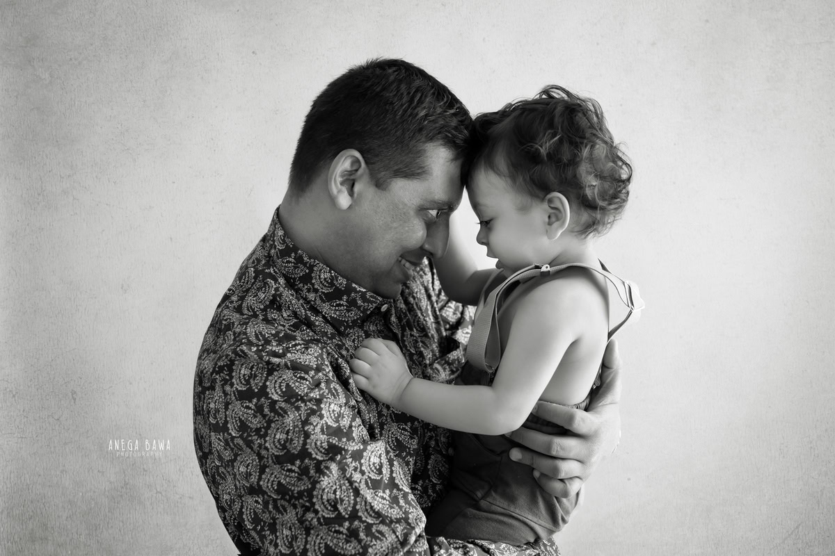 Adorable 10-month-old boy posing with dad against a soft beige backdrop, captured in a heartwarming family photoshoot by Anega Bawa, Gurgaon (Delhi, NCR)