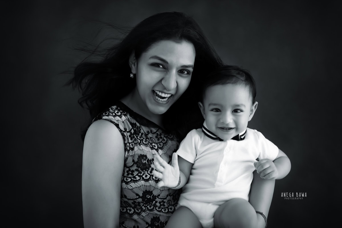 Charming 10-month-old boy posing cutely with mom against a black and white backdrop, in a delightful family photoshoot by Anega Bawa, Gurgaon (Delhi, NCR)
