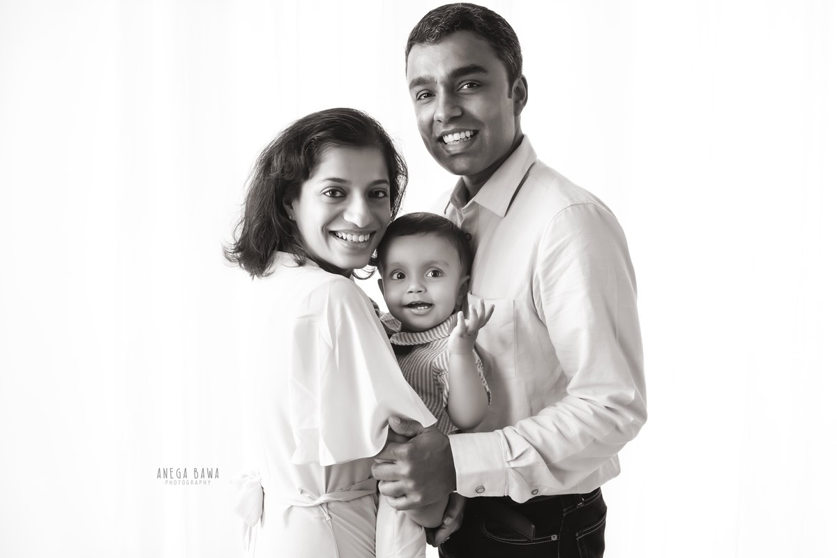 10-months-boy posing cute with parents against a serene white backdrop, captured during a family photoshoot in Gurgaon (Delhi NCR).