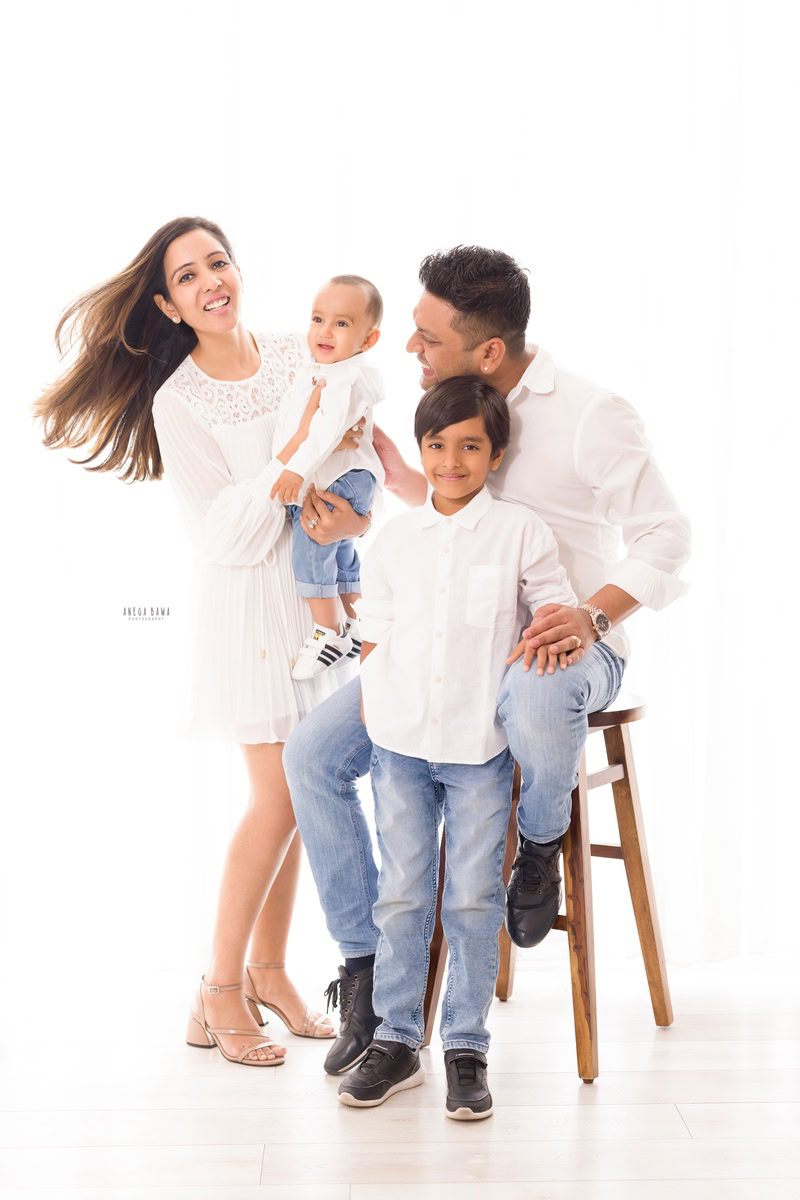 10-months-girl-posing-with-mom-dad-elder-brother-all-in-white-white-backdrop-family