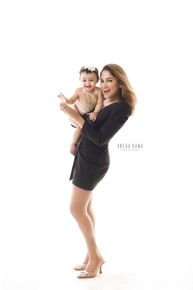 10-month-old girl posing with mom in a smiling pose against a crisp white backdrop, beautifully captured by Anega Bawa in Gurgaon (Delhi, NCR)