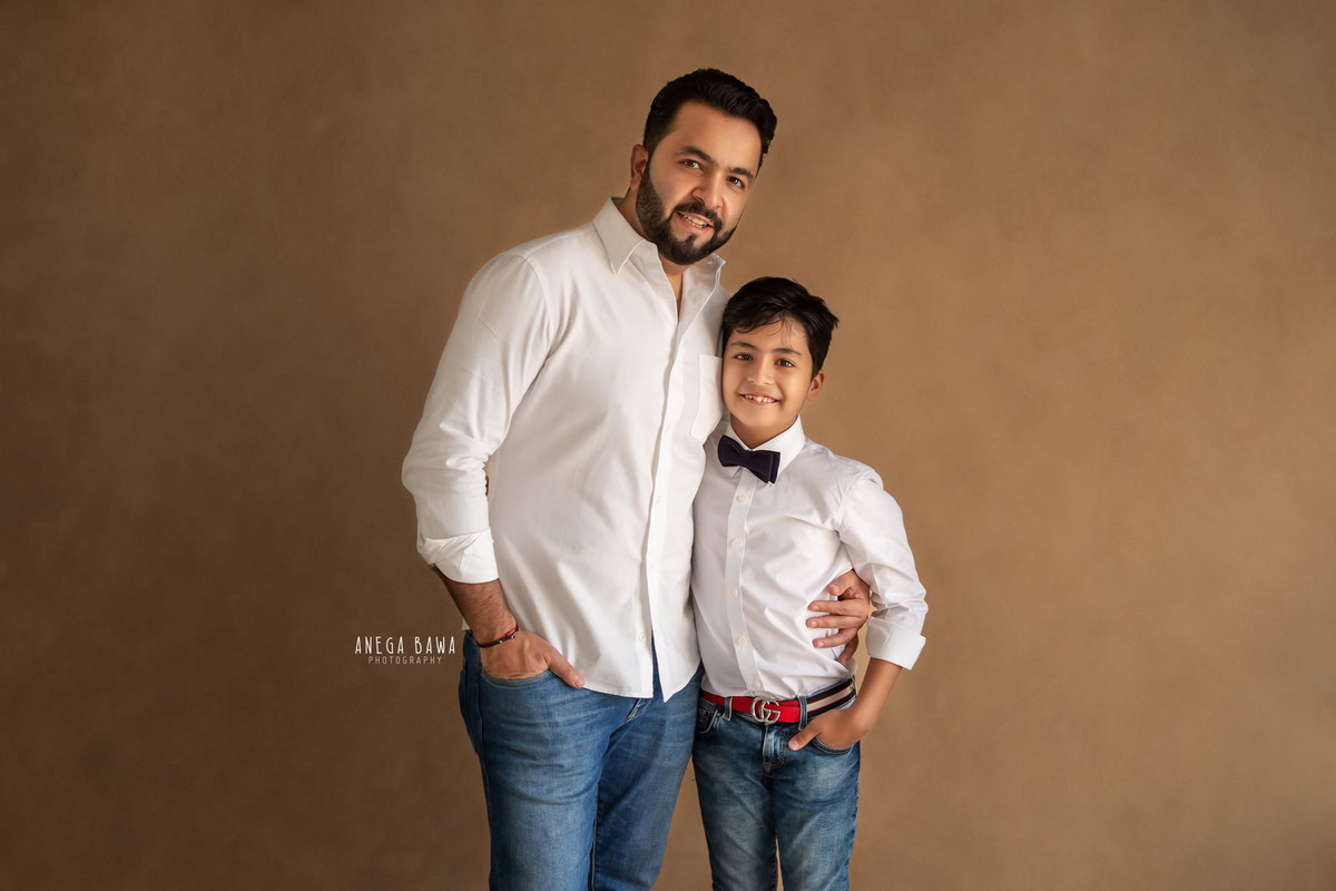 10-year-old boy posing with dad against a brown backdrop, captured by Anega Bawa family photographer Gurgaon (Delhi NCR).