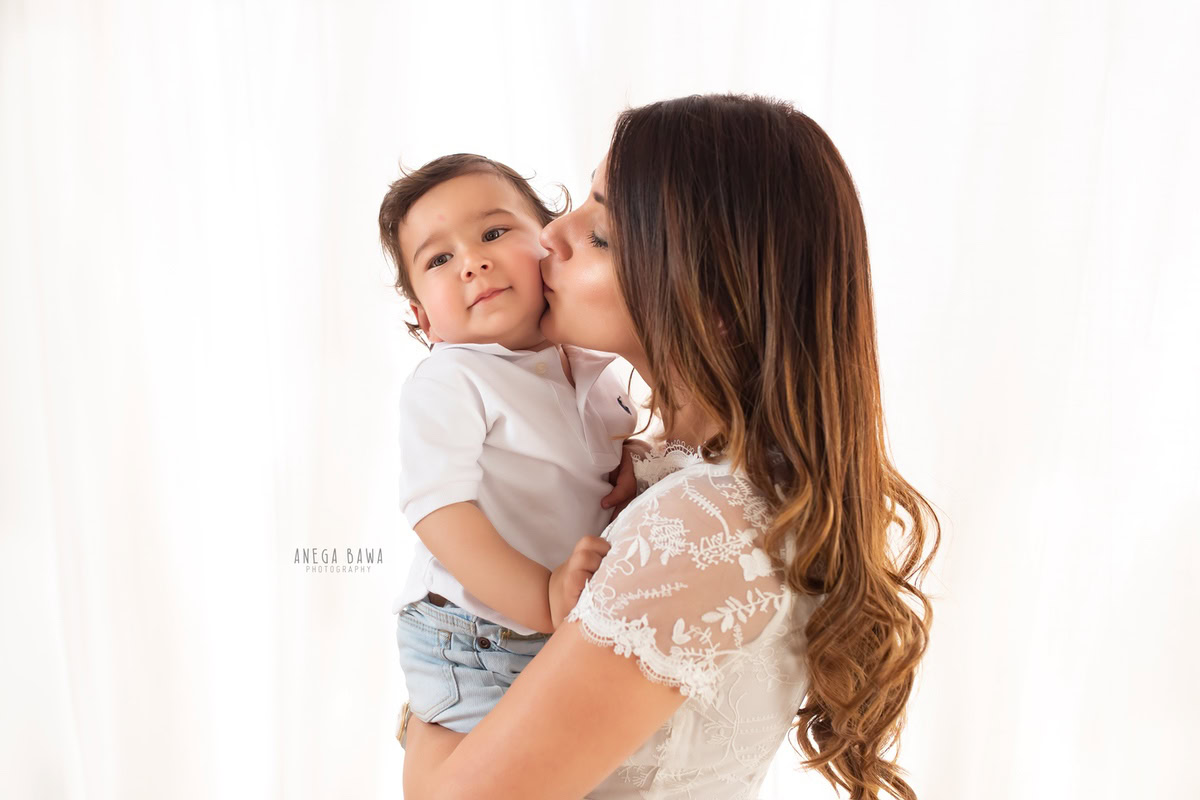 Adorable 12-month-old boy with mom in a loving pose against a clean white backdrop, captured by Anega Bawa Family Photographer Gurgaon (Delhi NCR).