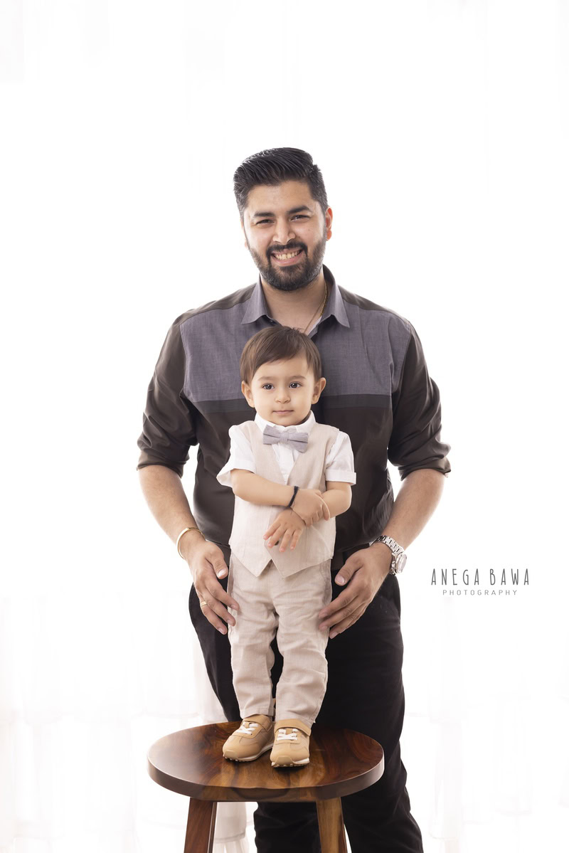 13-month-old boy standing on a wooden stool with dad against a white backdrop, photographed by Anega Bawa in Gurgaon (Delhi, NCR)