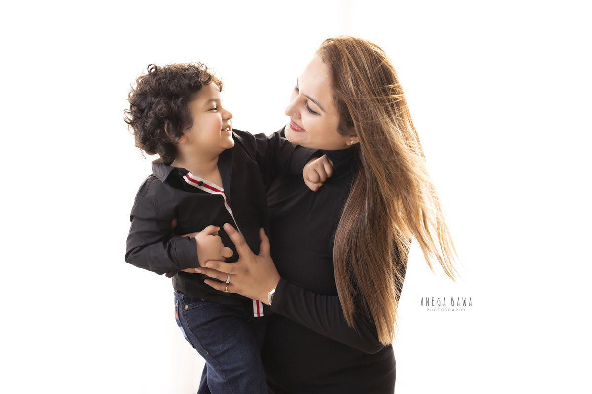 14-month-old boy posing with mom against a white backdrop, dressed in a black shirt, photographed by Anega Bawa in Gurgaon (Delhi, NCR)